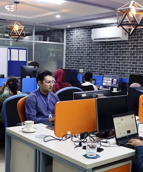 Office environment with team members working on computers, promoting flexible career-aligned learning, 24/7 support, and skill-focused growth through professional programs